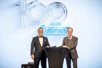 Diederik und Vincent Cuylits auf Bühne begrüßen die Gäste auf der Jubiläumsfeier im Alando Ballhaus vor Jubiläums-Logo